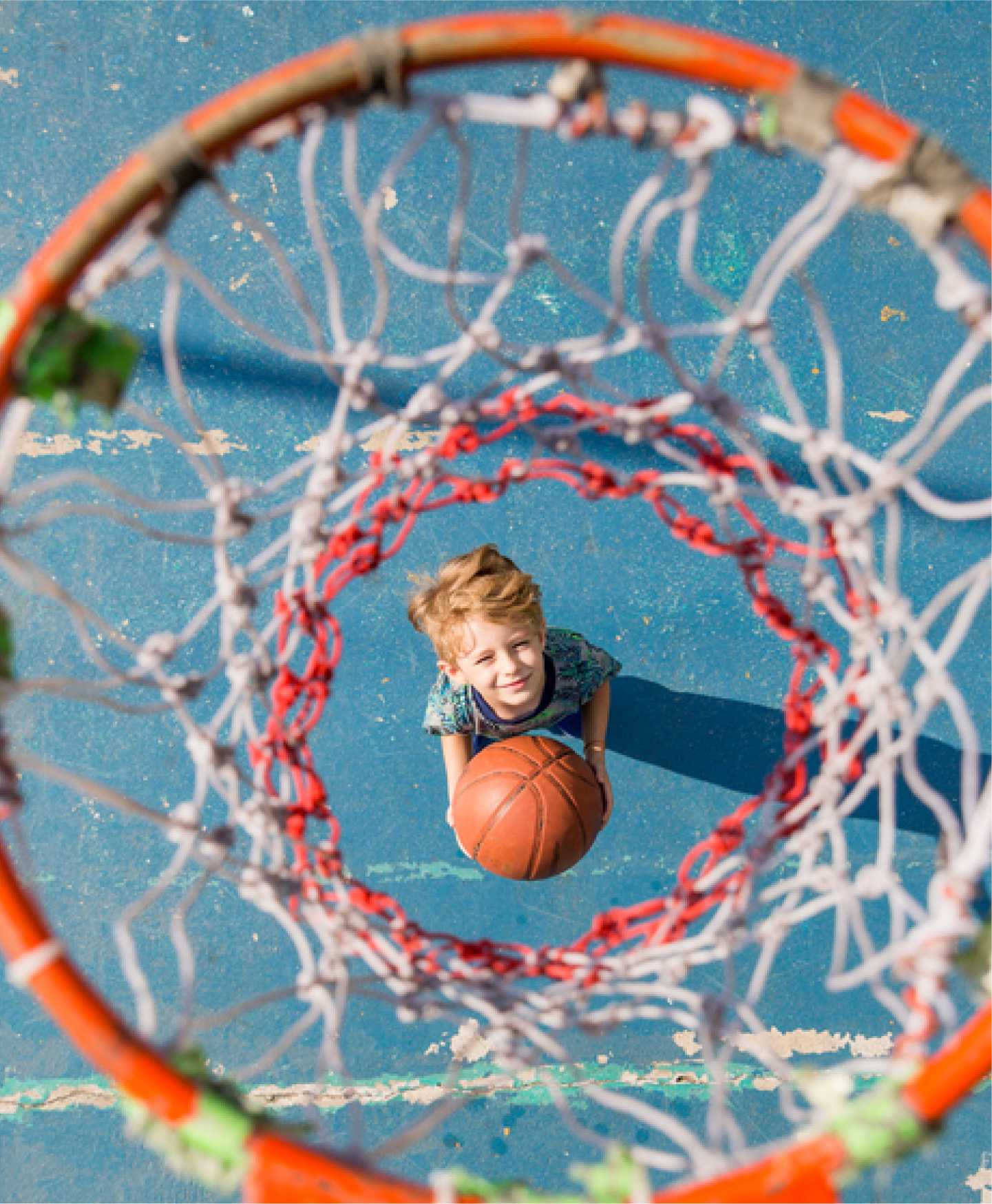 A child looks up through the hoop of a basketball net