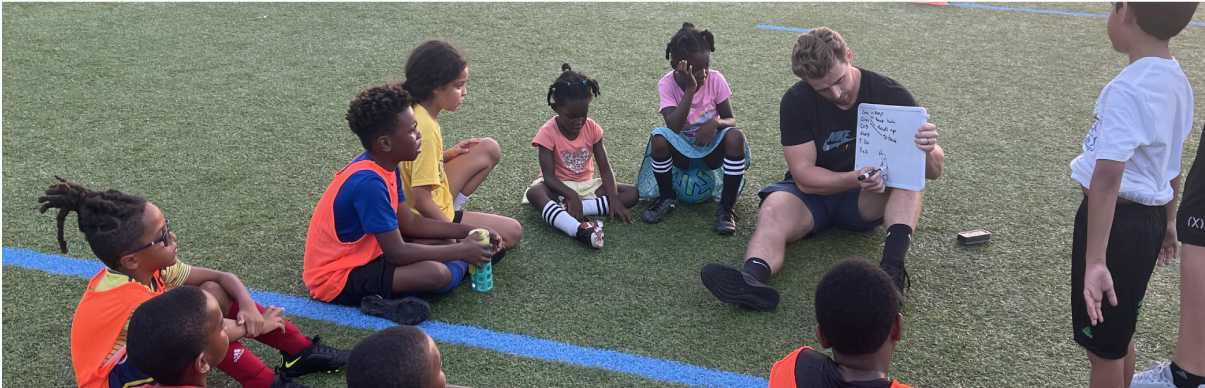 A coach shows a drawing of a strategy for a game to a group of children